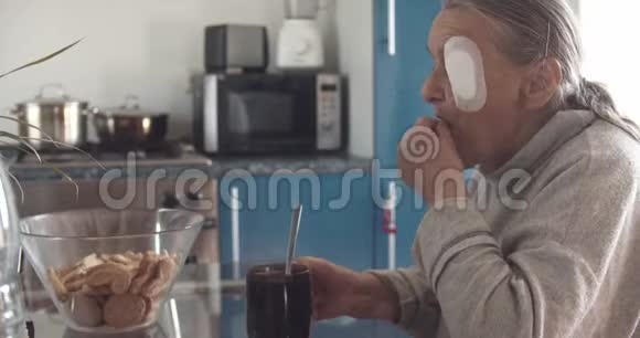 老太太眼睛受伤在厨房喝茶视频的预览图
