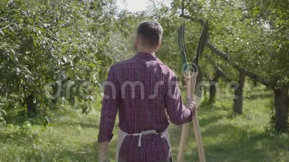 专业的留胡子的农民手里拿着铲子和草叉穿过花园农村生活观念视频的预览图