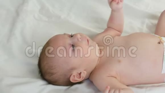 两个月的小婴儿躺在一张白色的床上美丽有趣的肖像妈妈给孩子穿衣服视频的预览图
