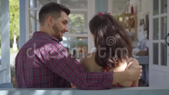 后景年轻的女人和男人坐在老房子的桌子旁那家伙拥抱了他的女朋友关系视频的预览图