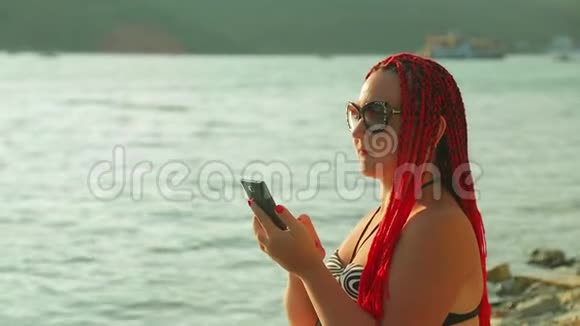 日落时分年轻的晒黑了的女人在湖边远程工作视频的预览图