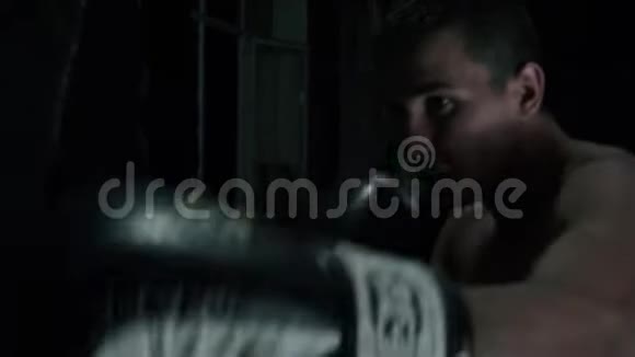 年轻强壮运动的拳击手在地下健身房打一个拳击袋视频的预览图