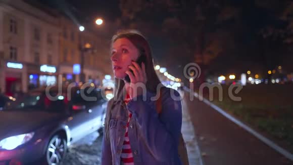 女人和她的朋友在智能手机上交谈试图在晚城的街道上找到他视频的预览图