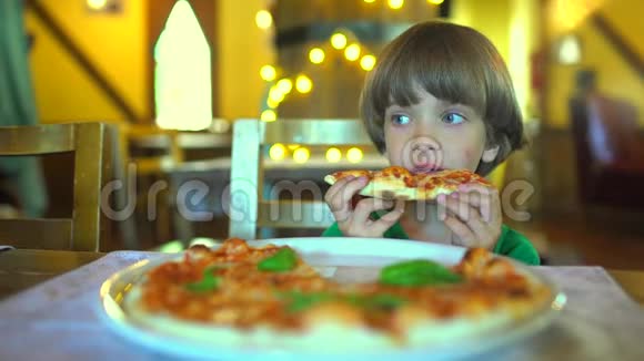 一个小孩子在快餐店吃披萨可爱有趣的白种人小男孩吃美味的意大利画视频的预览图