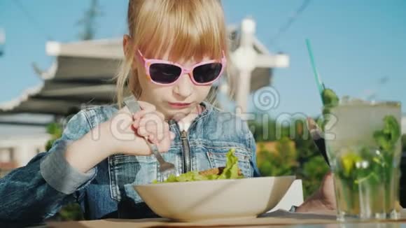 女孩在餐厅的夏季露台上吃了一份美味的沙拉带着婴儿的概念休息视频的预览图