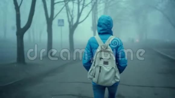 穿着蓝羽绒服带头罩和小城市背包的年轻运动女子视频的预览图