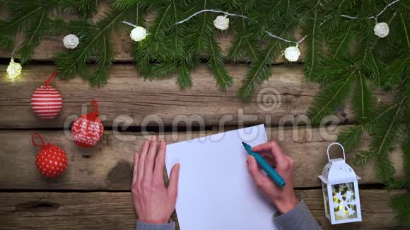 女人手在粗糙的风化木板上的白纸上写着圣诞框架视频的预览图