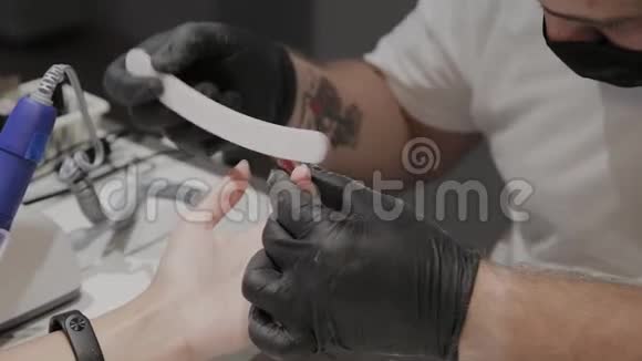 专业的美甲师男人用指甲锉打磨和抚平女孩指甲视频的预览图