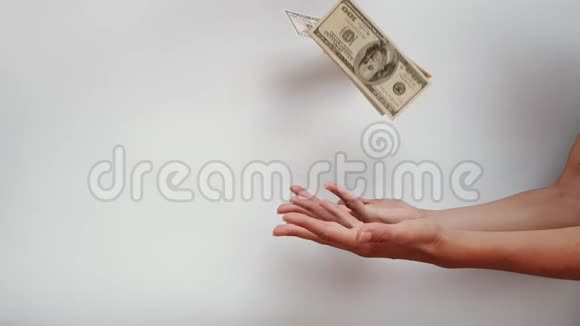 女人的手试图抓住下跌的美元钞票在白色背景下缓慢移动视频的预览图