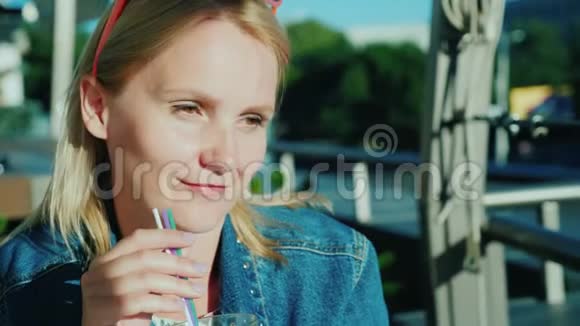女人用吸管喝鸡尾酒在咖啡厅的夏季露台上放松视频的预览图