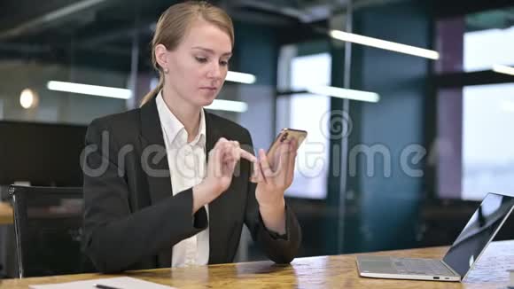 年轻女商人在办公室里使用智能手机视频的预览图