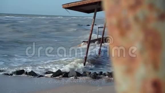摄像机从海滩上一个行走的女孩身后一根生锈的金属杆上抽出视频的预览图