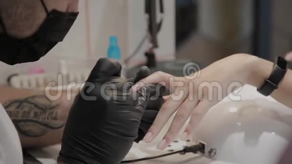 专业的美甲师男人给女孩涂指甲清漆视频的预览图