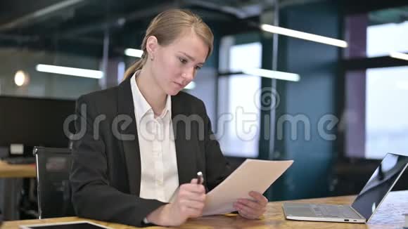 勤劳的年轻女商人在办公室读文件视频的预览图