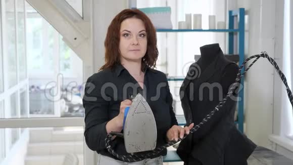 无缝的女人手里拿着铁在裁缝车间看着相机视频的预览图