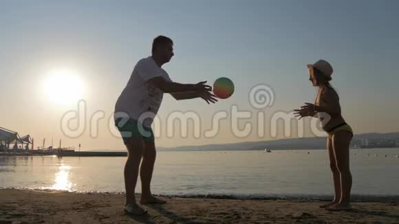 夏天一家人在海滩上打球父亲和女儿在户外踢足球友好家庭观念视频的预览图