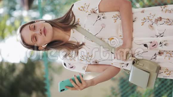 垂直视频穿着白色花裙的漂亮白种人棕色头发的女孩用手挽肩视频的预览图