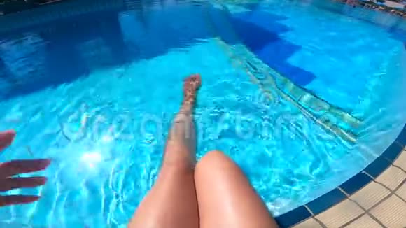 一个女人坐在游泳池旁摆动腿视频的预览图