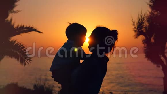背光男孩和他的母亲拥抱海洋日落视频的预览图