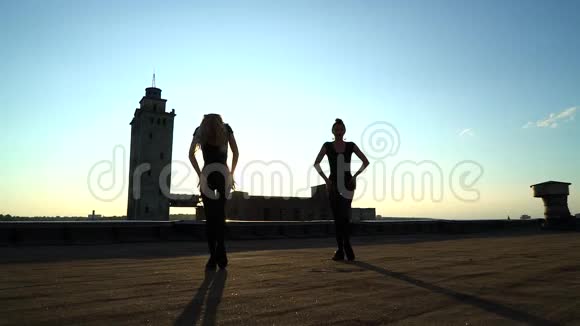 日落时分穿着紧身衣在屋顶上跳舞的女人身上的光芒视频的预览图