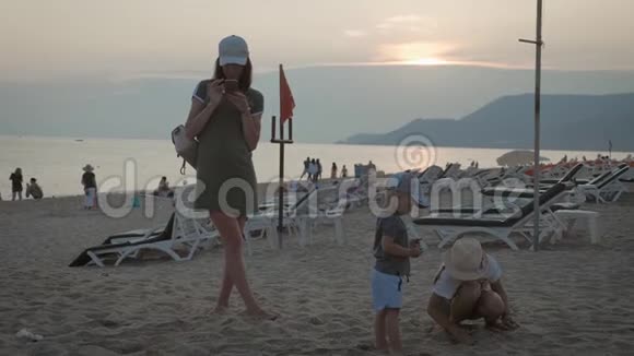 幸福的家庭母亲和两个孩子在海滩度假日落时分母亲和两个孩子在海里视频的预览图