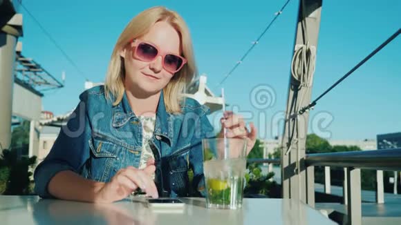 一个女人用智能手机在夏天的咖啡馆里休息假期概念的联系视频的预览图