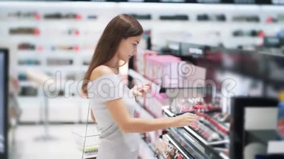 可爱的女人选择口红在化妆品店试穿慢动作视频的预览图