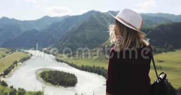 女徒步旅行者欣赏风景如画的自然景观在山谷与河流视频的预览图