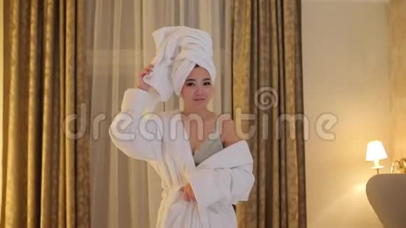 一个亚洲女孩穿着白色浴袍站在卧室里视频的预览图