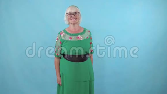 戴眼镜的老年妇女用蓝色背景的手指表示赞同视频的预览图