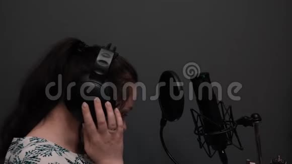 年轻迷人的黑发女孩正在耳机里听音乐白种人女人的肖像正在听录音Vo视频的预览图