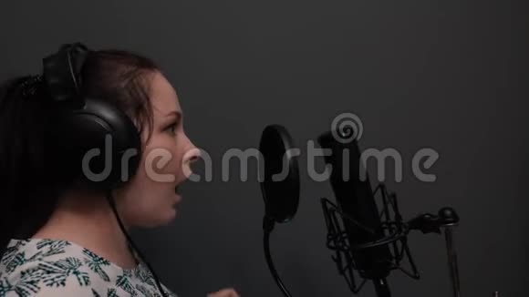 年轻浪漫的流行女歌手正在表演歌曲女孩在家里的专业录音室唱歌灰色的墙壁教授视频的预览图