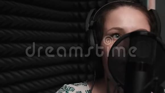 在声乐室里闭上蓝眼睛的迷人女孩年轻女子在录音室录制歌曲录音记录声音视频的预览图