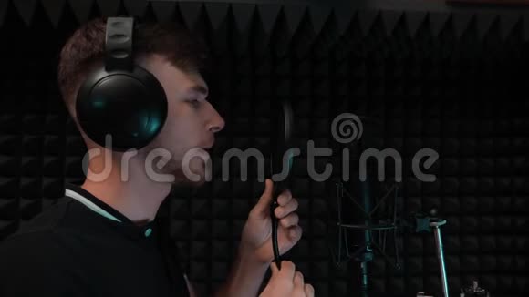 年轻英俊的白种人男孩正在准备录制歌曲戴着耳机的歌手开始在录音室唱歌慢一点视频的预览图