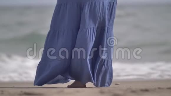 女人蓝色的裙子在海岸的风中发展视频的预览图