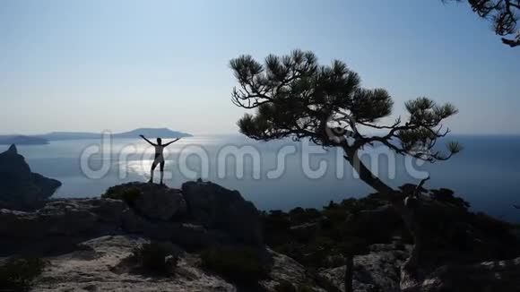 一位年轻受启发的女人站在海面上的山顶上举起双手对着大海视频的预览图