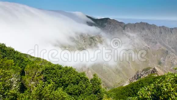 云层在高山峰之间和低于高山峰之间飞行的4K景观上面长满了树木和森林完美完美完美视频的预览图