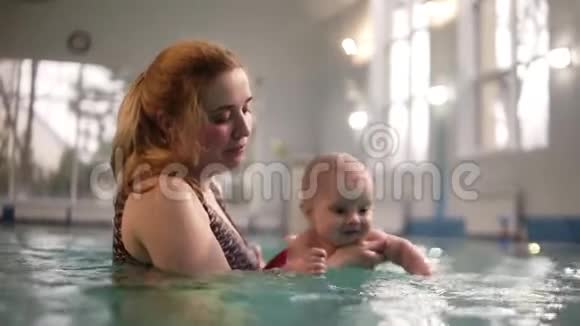 年轻的妈妈教她可爱的小男孩在游泳池里潜水这孩子很高兴孩子的成长为人父母视频的预览图