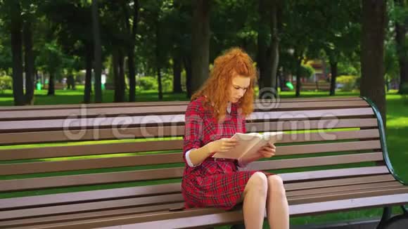 在绿色公园读悲伤书的漂亮女孩视频的预览图