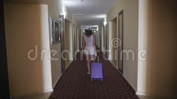 旅行者女孩带着手提箱在酒店走廊散步视频的预览图