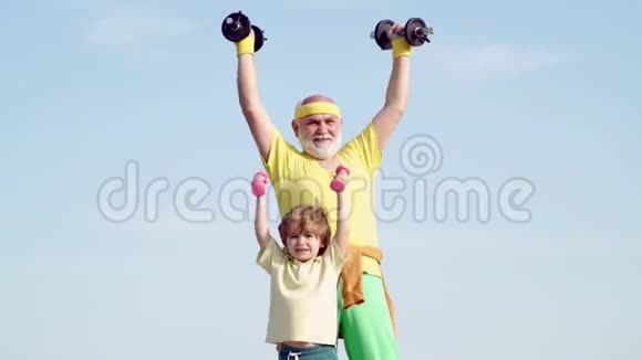 祖父和孙子手里拿着哑铃孩子们在爷爷之后重复锻炼健康的家庭生活方式视频的预览图