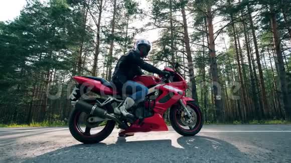 摩托车手坐在路上的红色自行车上视频的预览图