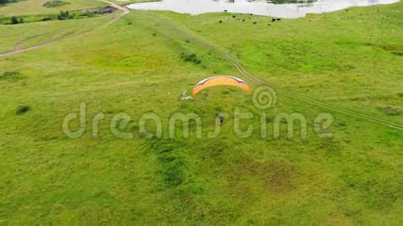 宽敞的草地上有一个人在飞翔草甸之上的滑翔伞视频的预览图