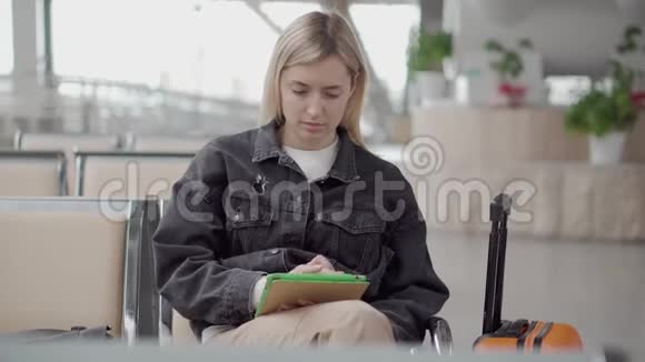 一个人坐在车站候车厅里女人正在用平板电脑查看电子邮件视频的预览图