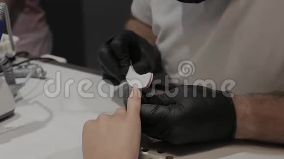 专业的美甲师男人用指甲锉打磨和抚平女孩指甲视频的预览图