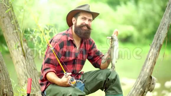 特劳特英俊的渔夫拿着鱼竿在河里钓鱼钢头虹鳟快乐男人的肖像视频的预览图