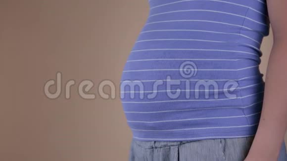 一个穿着蓝色T恤的孕妇腹部的特写镜头上面出类似的标志文本复制空间视频的预览图