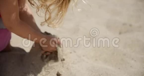一个小女孩在海滩上慢镜头手里拿着沙子让它再次落在沙子上4k慢镜头视频的预览图