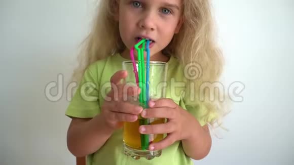 快乐的女孩用吸管在一杯苹果汁里泡泡万向节运动视频的预览图