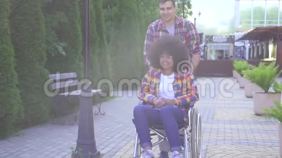 一位积极微笑的年轻非裔美国妇女的肖像残疾于轮椅上她的朋友欢欣鼓舞视频的预览图